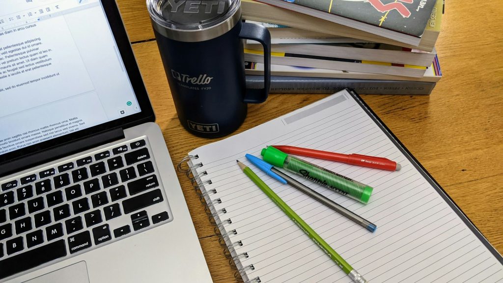 Laptop, notebook and coloured pens on a desk