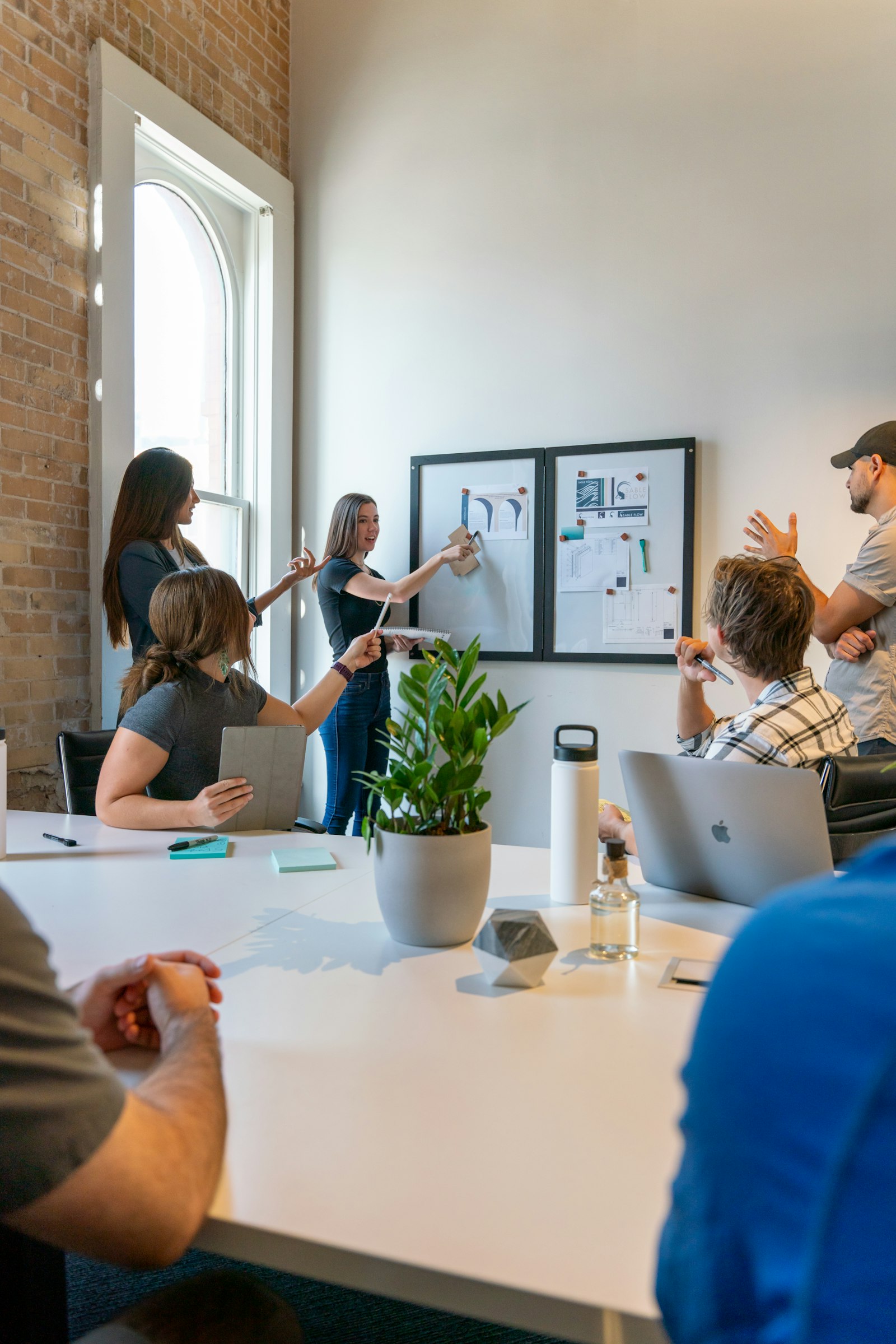 Small editorial team planning around a white table with a whiteboard