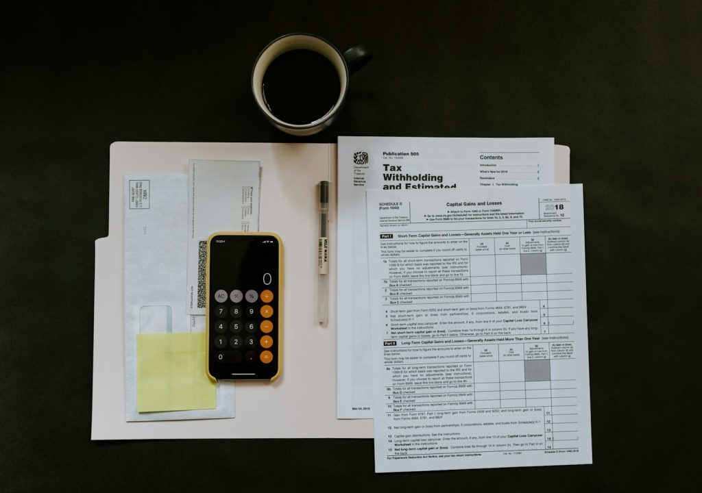 Tax forms, calculator and pen on a desk