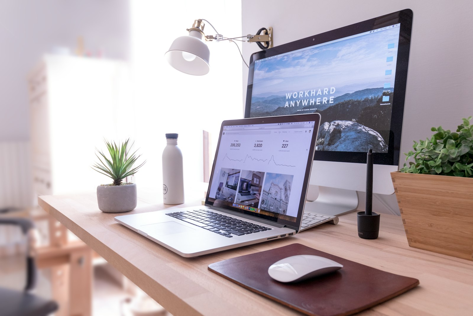 Tidy home office desk with a laptop, monitor and plants