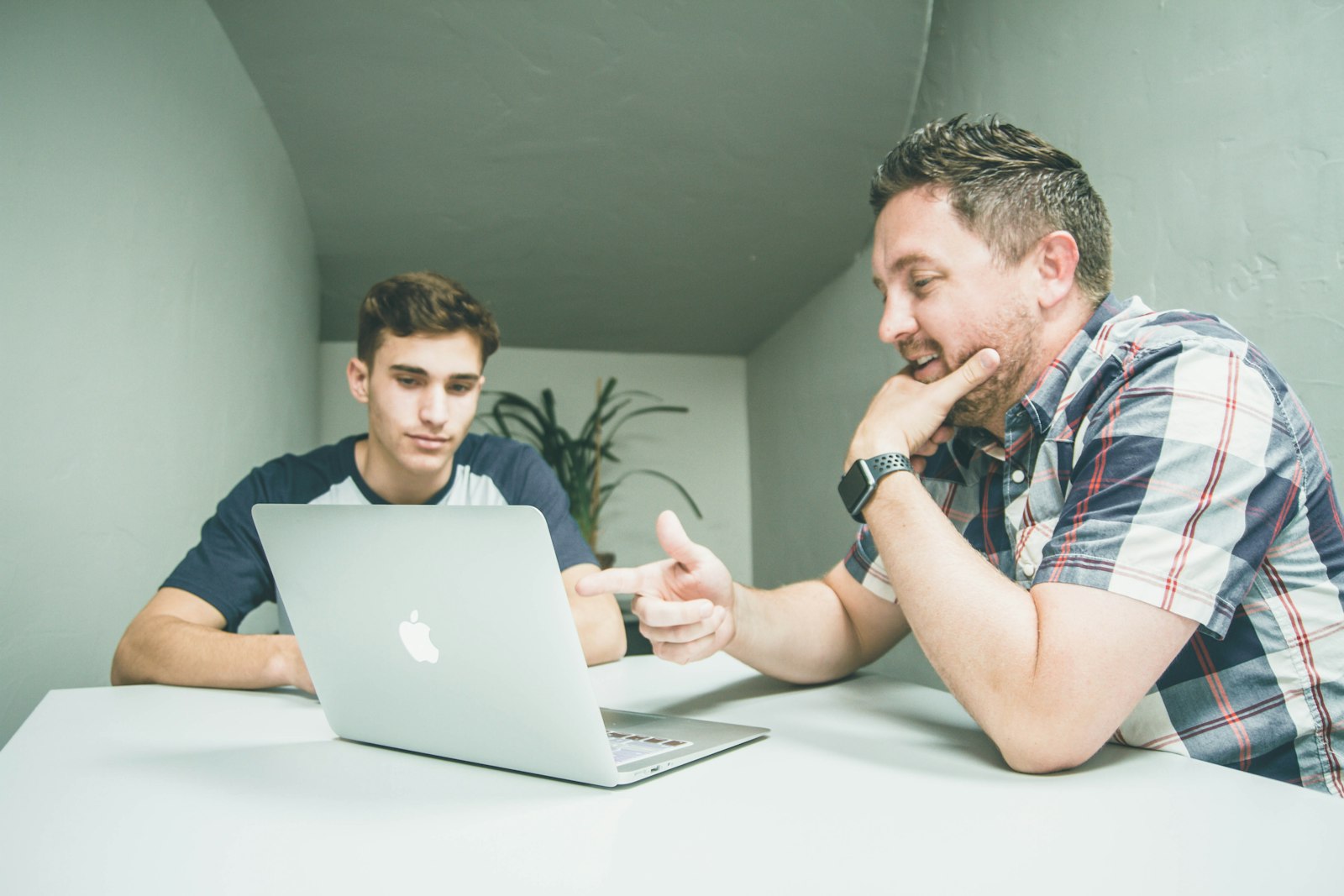 Mentor pointing at a laptop screen while explaining a task to a young learner