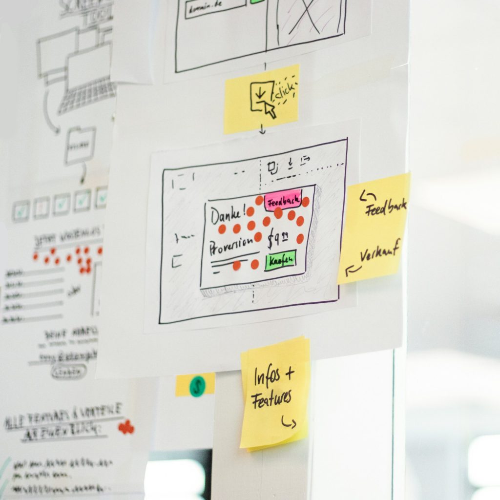 Hand-drawn app wireframes with sticky notes on a glass board