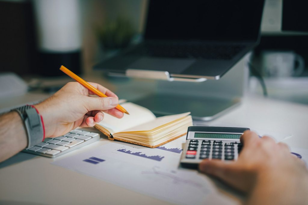 Person working out prices with a calculator and notebook