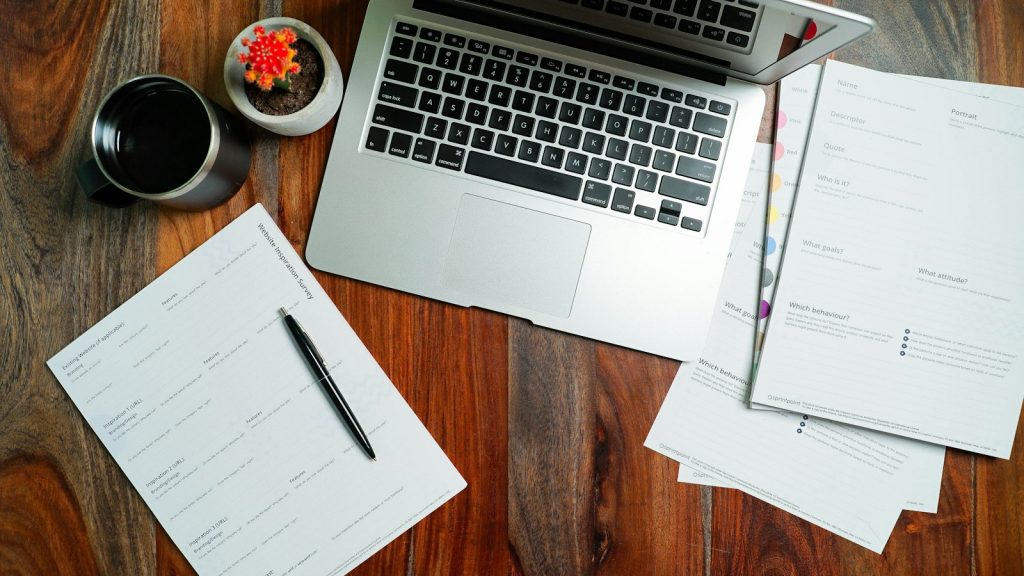 CV documents and a laptop on a wooden desk