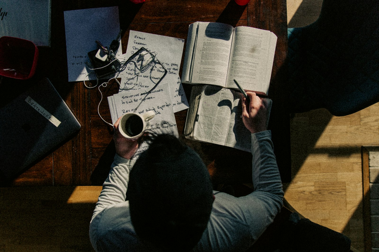 Researcher reading books and taking notes at a desk, seen from above