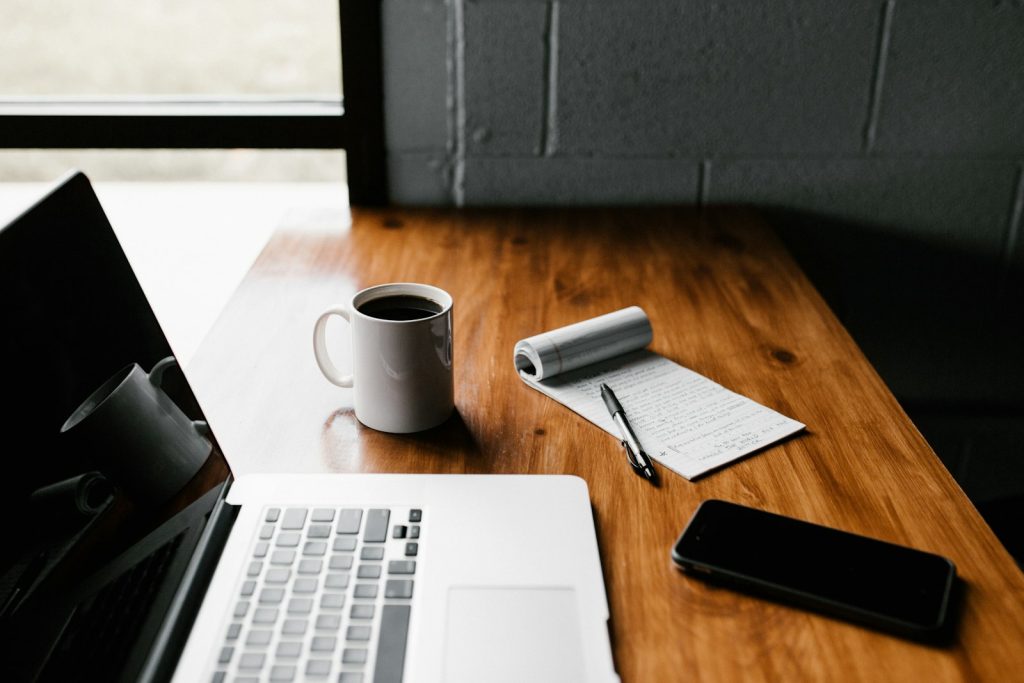 Laptop, coffee mug and phone on a wooden desk ready for blog writing