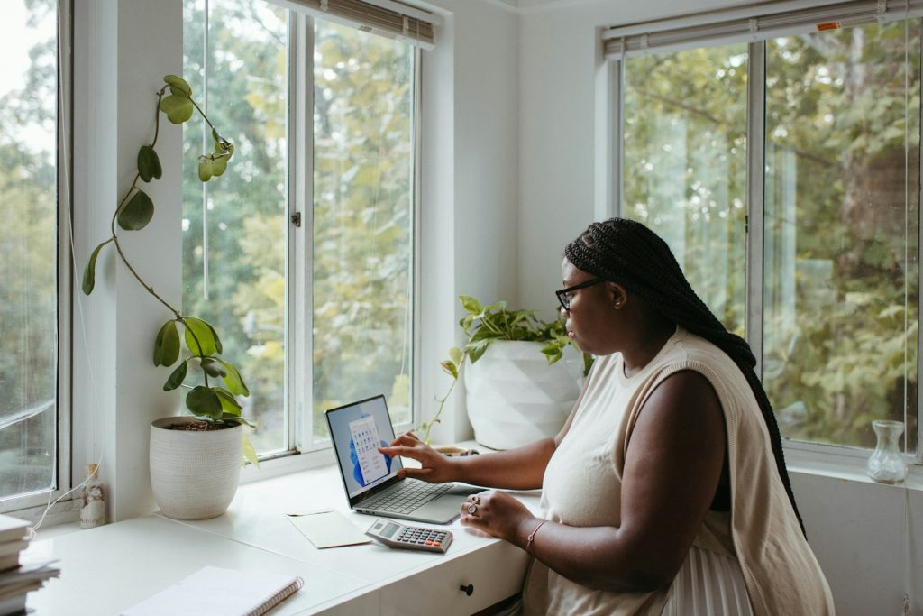 Woman working on a laptop at a table in a bright room