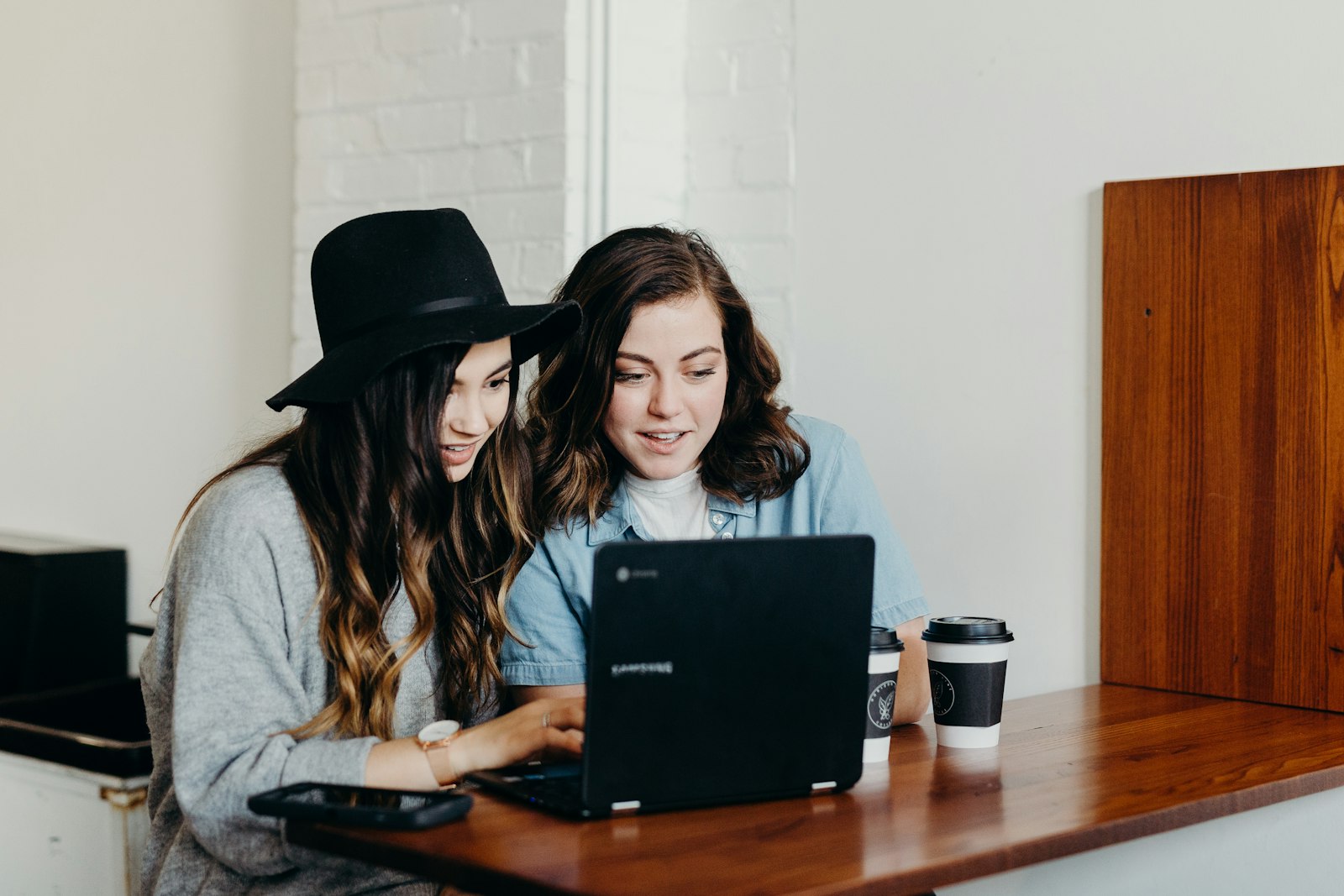 Two young women learning together on a laptop at a table