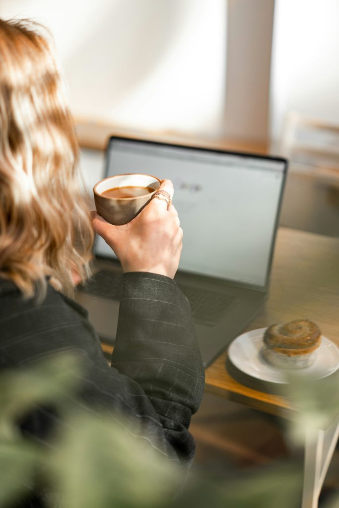 Woman writing at a laptop with a coffee cup